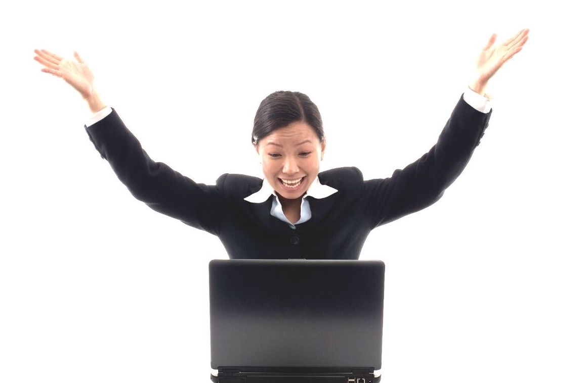 an image of a women excitedly looking at her laptop with her arms raised in the air
